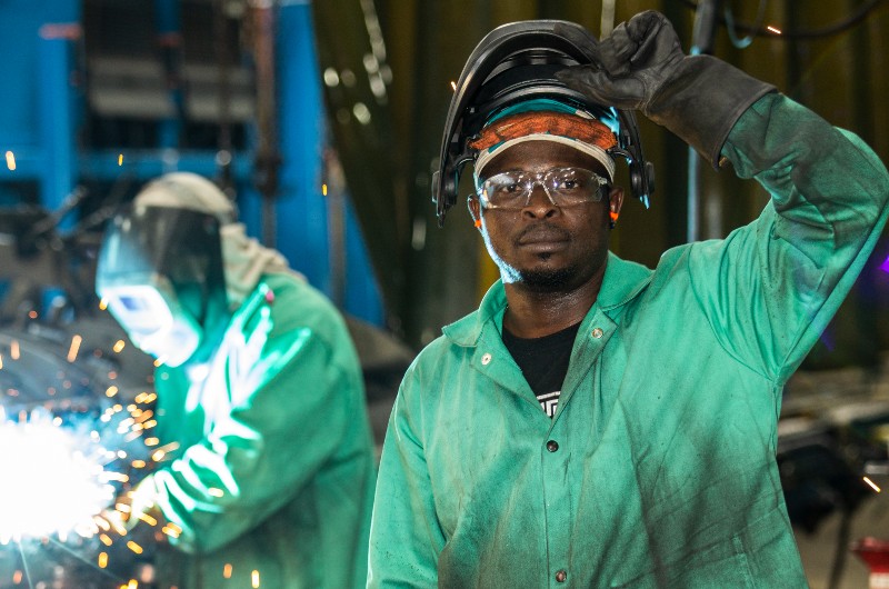 A welder lifting up his mask